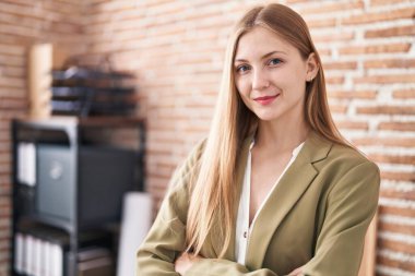 Young caucasian woman business worker standing with arms crossed gesture at office