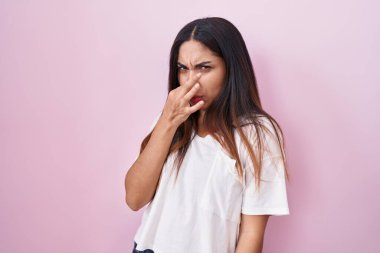 Pembe arka planda duran genç Arap kadın pis ve iğrenç bir koku alıyor. Nefesini burnunda tutuyor. Kötü kokuyor. 