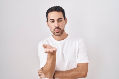 Yakışıklı İspanyol bir adam beyaz arka planda dikiliyor kameraya bakıyor ve havada bir öpücük savuruyor. Güzel ve seksi. aşk ifadesi. 