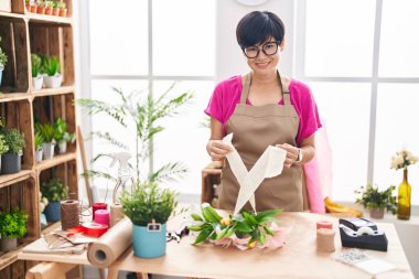 Middle age chinese woman florist make bouquet of flowers at flower shop