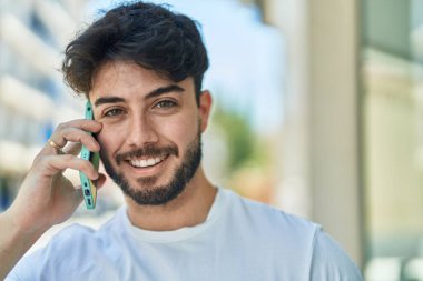 Genç İspanyol adam gülümsüyor. Kendine güveniyor. Sokakta akıllı telefondan konuşuyor.