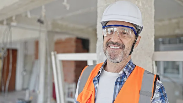 中年男人建筑商自信地站在建筑工地微笑 — 图库照片