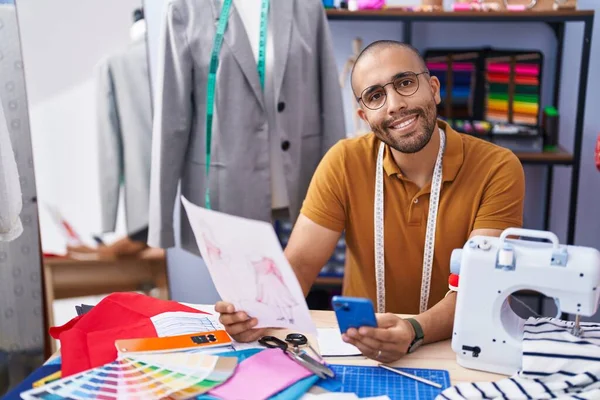 Young Latin Man Tailor Using Smartphone Looking Clothing Design Atelier — Stockfoto