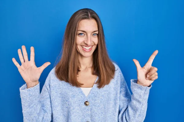 Młoda Kobieta Stoi Nad Niebieskim Tle Pokazując Wskazując Palcami Numer — Zdjęcie stockowe