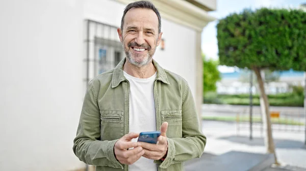 中年男性笑顔自信を持って使用してスマートフォンでストリート — ストック写真