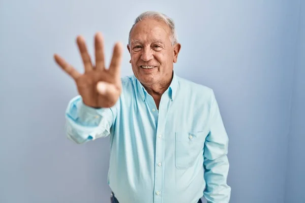 一个白发苍苍的老人站在蓝色的背景上 用第四指尖 面带微笑 自信而快乐 — 图库照片