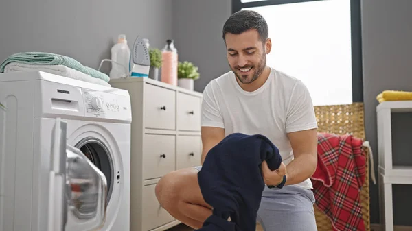 若いヒスパニック系の男は洗濯室で自信を持って洗濯服を笑って — ストック写真