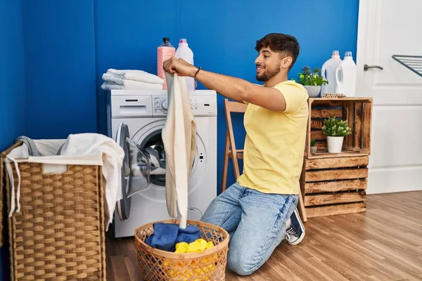 年轻的阿拉伯男子拿着毛衣在洗衣房洗衣服 — 图库照片