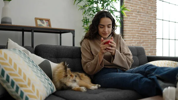 Jovem Hispânica Com Cão Cheirando Xícara Café Sentado Sofá Casa — Fotografia de Stock