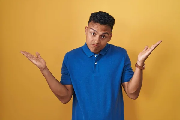 Young Hispanic Man Standing Yellow Background Clueless Confused Expression Arms — Stock Photo, Image