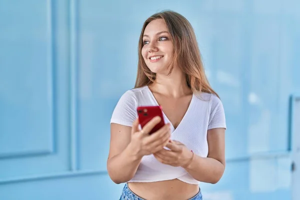 Junge Blonde Frau Lächelt Selbstbewusst Mit Smartphone Über Isolierten Blauen — Stockfoto