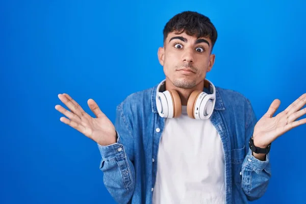Young Hispanic Man Standing Blue Background Clueless Confused Expression Arms — Foto Stock