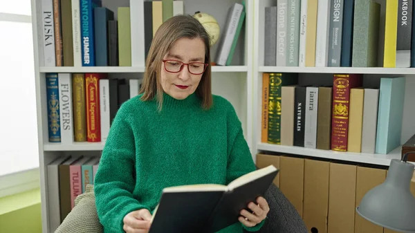 一个满头白发的惊慌失措的女人坐在图书馆里看书 — 图库照片