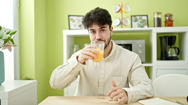 若いですヒスパニック男飲むオレンジジュースでダイニングルーム — ストック写真