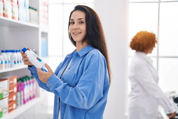 两名女药剂师和一名女顾客在药店拿着药瓶 — 图库照片