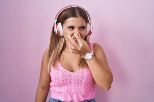 Young Blonde Woman Listening Music Using Headphones Smelling Something Stinky — Stock Photo, Image