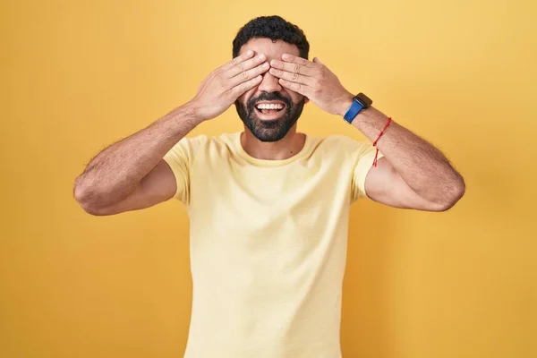 Hispanic Man Beard Standing Yellow Background Covering Eyes Hands Smiling — Stockfoto