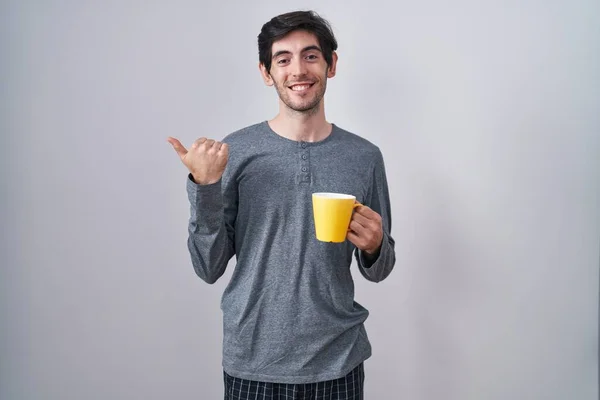 Młody Latynos Piżamie Pijący Filiżankę Kawy Skierowanej Tyłu Rękami Kciukami — Zdjęcie stockowe