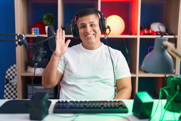 若いヒスパニック系の男がビデオゲームをしているこんにちは幸せと笑顔 優しい歓迎ジェスチャー — ストック写真