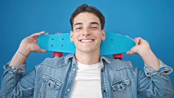 Jovem Hispânico Homem Sorrindo Confiante Segurando Skate Sobre Fundo Azul — Fotografia de Stock