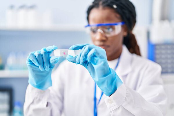 Африканская американка-ученый держит образец в лаборатории