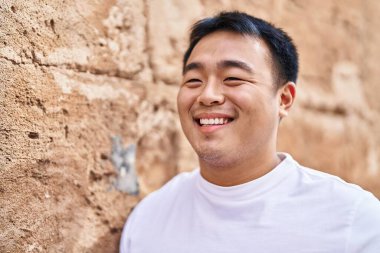 Young chinese man smiling confident standing at street