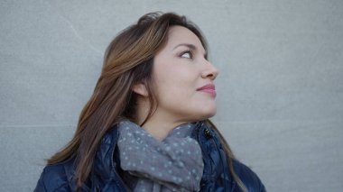 Genç, güzel İspanyol bir kadın, kendinden emin bir şekilde, izole beyaz arka planda, gökyüzüne bakıyor.