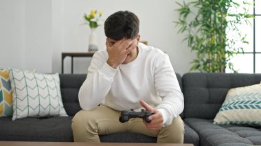 Evde video oyunu oynayan İspanyol genç adam stresli.