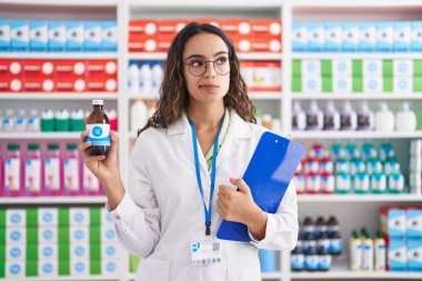 Eczanede çalışan genç İspanyol kadın elinde şurup, gülümsüyor ve yan tarafa bakıyor.. 