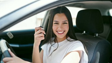 Genç, güzel, İspanyol bir kadın gülümsüyor. Elinde yeni arabanın anahtarı var.