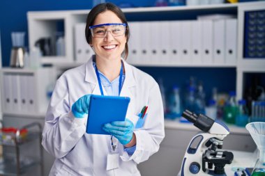 Young woman scientist using touchpad at laboratory