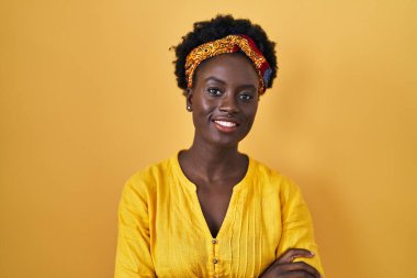 Afrikalı, sarıklı, mutlu yüzlü, kollarını kavuşturup kameraya bakan genç bir Afrikalı kadın. pozitif kişi. 