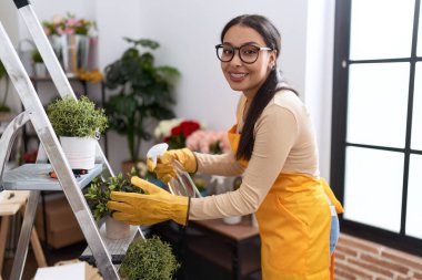 Çiçekçide dağıtıcı sulama bitkisi kullanan genç Arap kadın çiçekçi.
