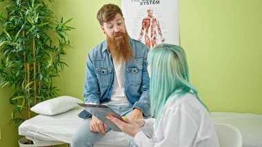 Kadın ve erkek doktor ve hasta klinikte tıbbi raporları okuyorlar.