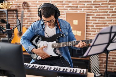 Müzik stüdyosunda elektro gitar çalan genç bir sanatçı.