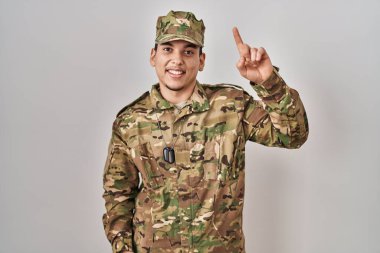Kamuflaj üniforması giyen genç bir Arap başarılı bir fikirle işaret ediyor. Heyecanlı ve mutlu. Bir numara.. 