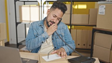 Genç Latin bir iş adamı ofiste telefonla konuşuyor.