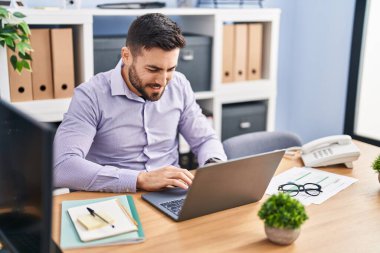 Young hispanic man business worker using laptop working at office