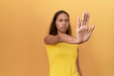 Genç Afro-Amerikalı kadın, el hareketlerini durdurup izole edilmiş sarı arka planı teslim ediyor.