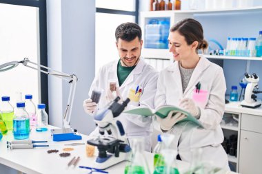 Man and woman wearing scientist uniform working at laboratory