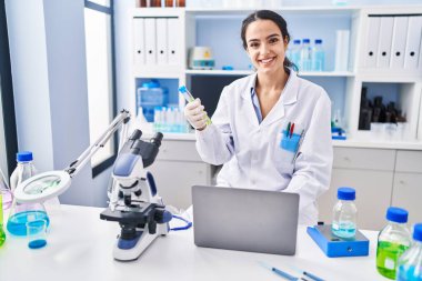 Laboratuvarda çalışan, bilim adamı üniforması giyen genç İspanyol kadın.