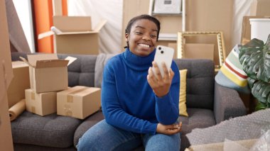 Afrikalı Amerikalı bir kadın yeni evindeki koltukta video görüşmesi yapıyor.