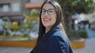 Sokakta kendinden emin gülümseyen genç İspanyol kadın.