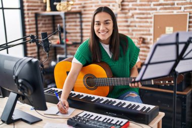 Genç İspanyol kadın müzisyen müzik stüdyosunda klasik gitar çalıyor.