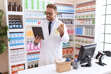 Eczanede dokunmatik ped kullanan orta yaşlı bir eczacı.