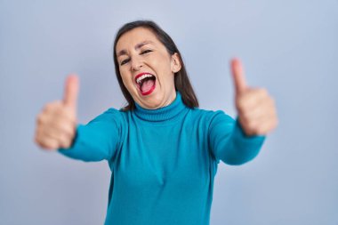 Orta yaşlı İspanyol bir kadın izole edilmiş arka planda durup elleriyle olumlu jest yapmayı onaylıyor, gülümsüyor ve başarı için mutlu. kazanan jest. 