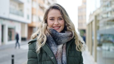 Sokakta kendine güvenen genç sarışın kadın gülümsüyor