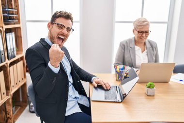 Ofiste çalışan Latin asıllı genç adam gururla bağırıyor, zaferi kutluyor ve kollarını kaldırarak heyecanlanıyor. 