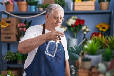 Çiçekçide çalışan dağınık saçlı, kır saçlı çiçekçi.