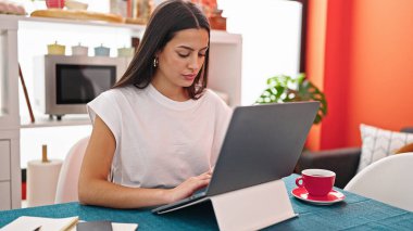 Yemek odasındaki masada dizüstü bilgisayar kullanan güzel İspanyol kadın.